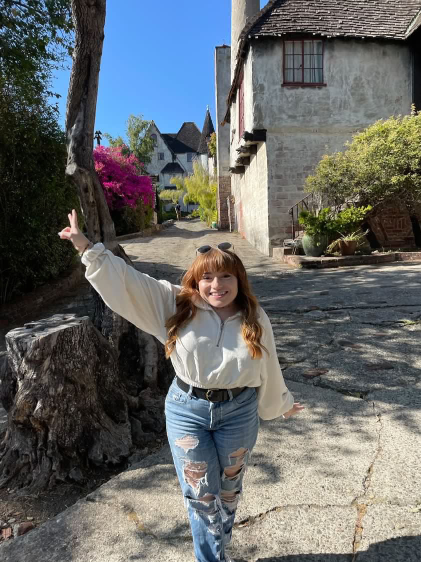 A short stature woman with SED Dwarfism poses in a summery scene.