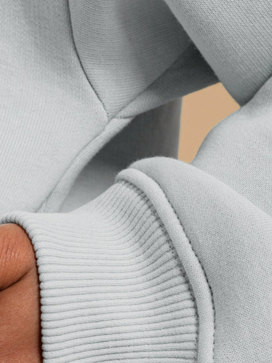 Close-up of a hand partially covered by the cuff of the DEWEY BAILEY Crewneck Sweatshirt Jumper (Grey, Petite & Extra Petite), highlighting the ribbed texture and seams of its relaxed fit fabric.