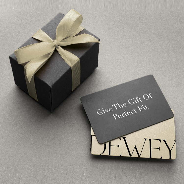 A black gift box with a cream ribbon sits next to two overlapping gift cards. The top card reads "Give The Gift Of Perfect Fit" in white text on a black background.