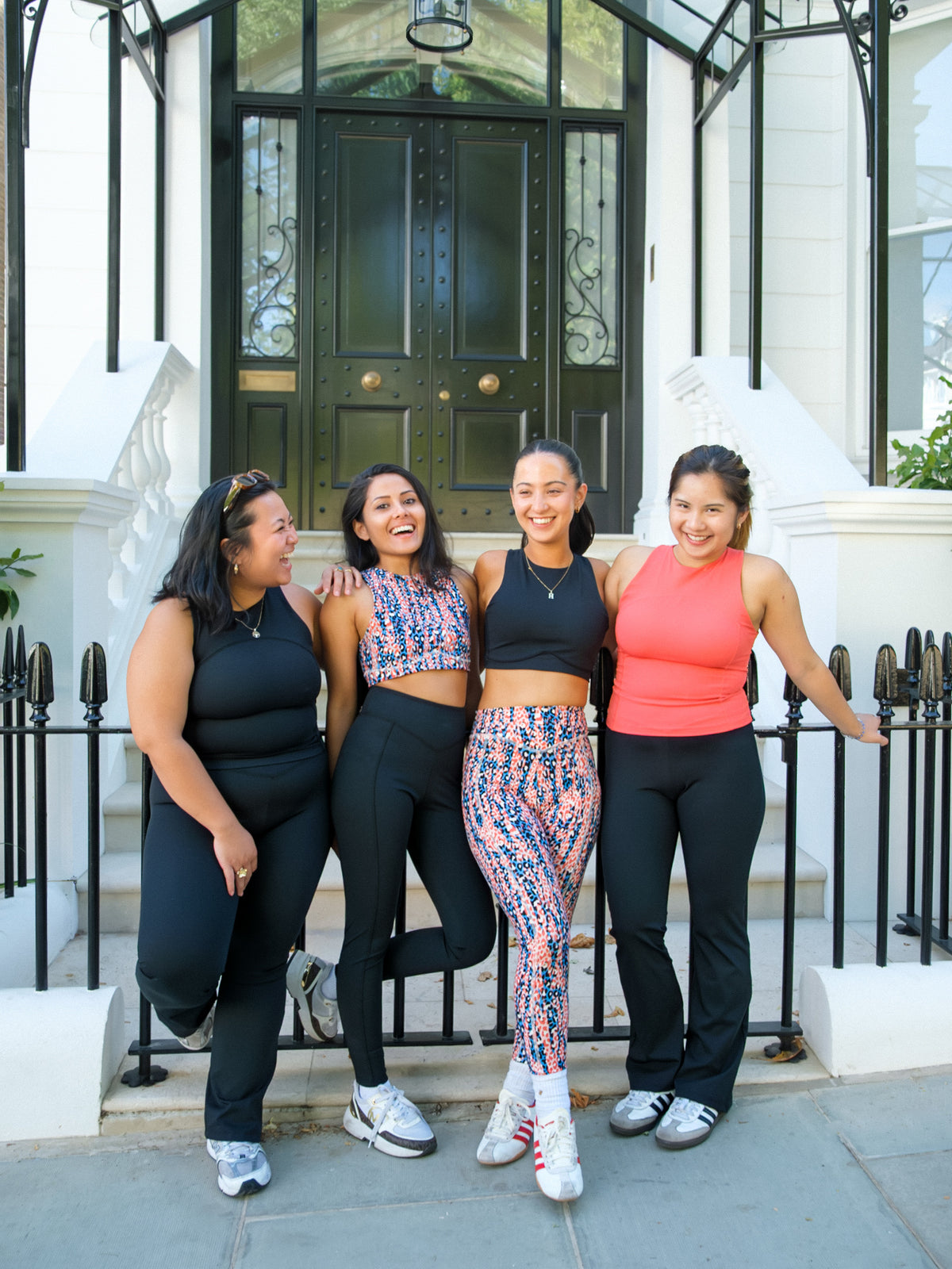 Four women in athleisure stand together outdoors, each showing off their favorite DEWEY IRIS High Waist Leggings (Printed, Extra Petite) and enjoying the sunny day.