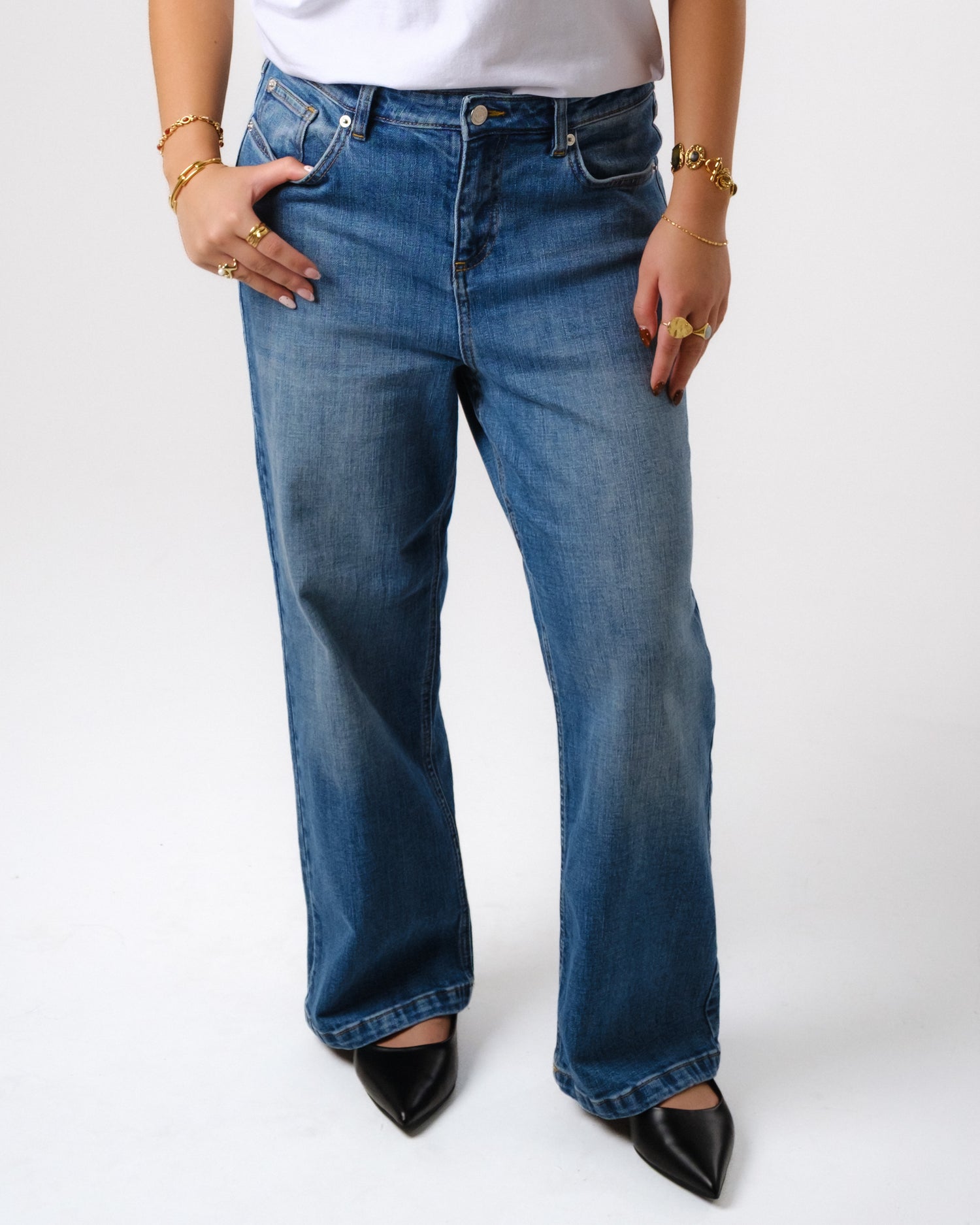 a person wearing blue jeans and gold jewelry
