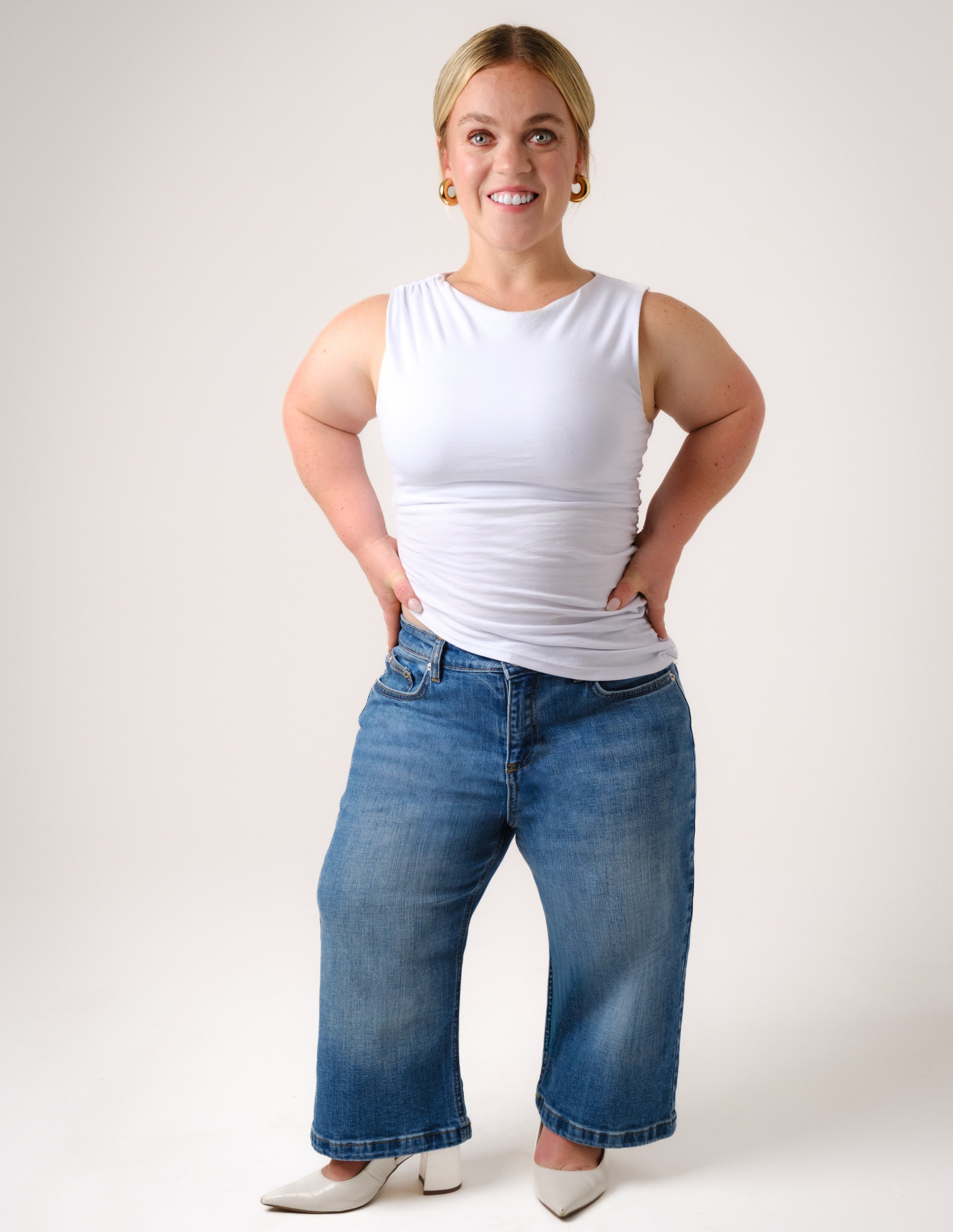 a woman in a white tank top and blue jeans