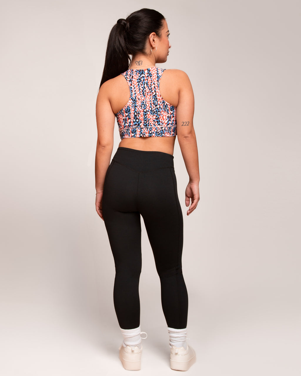 a woman in black pants and a colorful tank top
