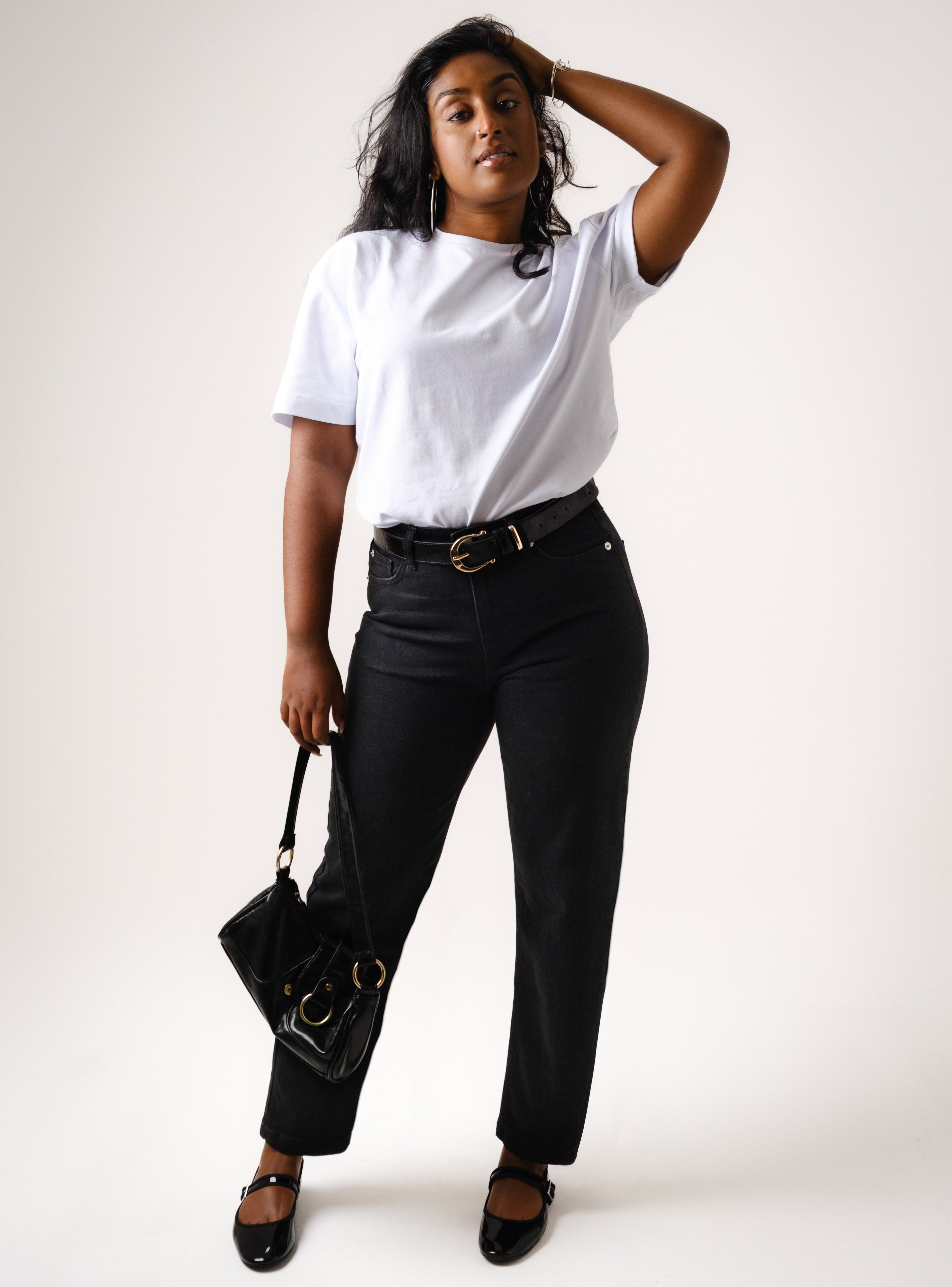 a woman in white shirt and black pants holding a purse