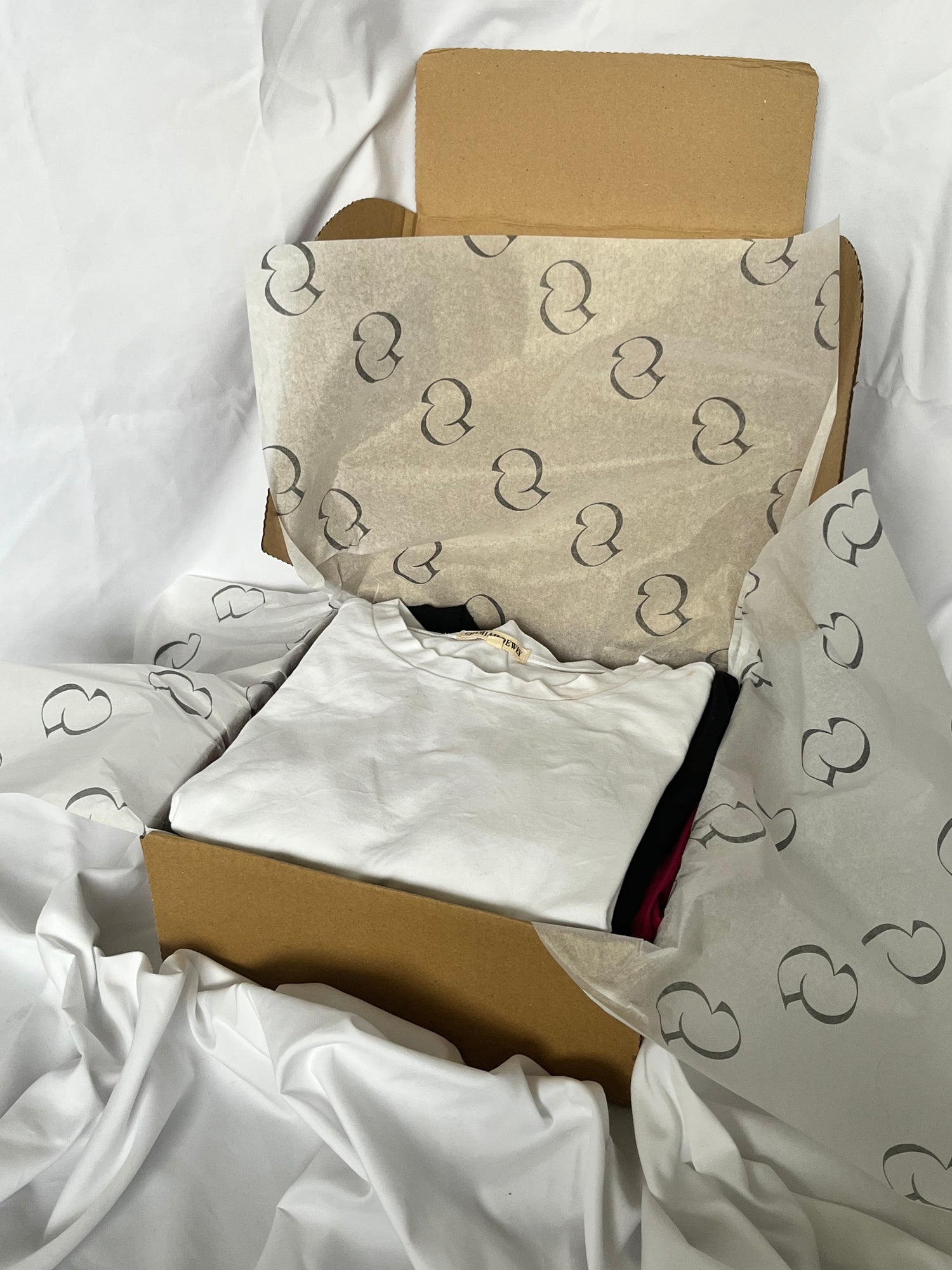 box with branded tissue paper woth folded white tshirt inside